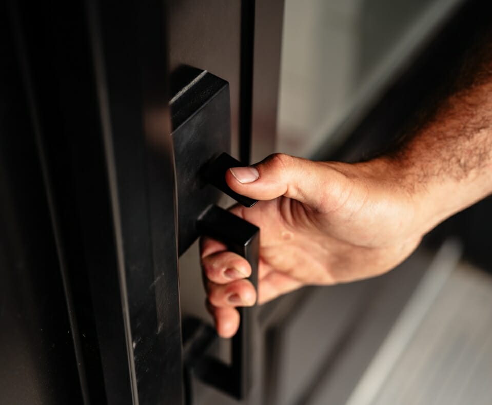 Une main masculine tiens la poignée d'un porte de logement