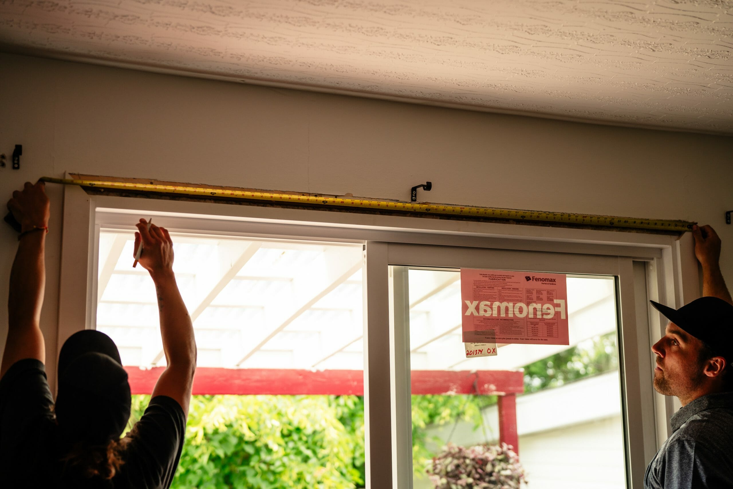 Un homme et une femmes utilisent un mètre à mesurer pour la réparation de fenêtres