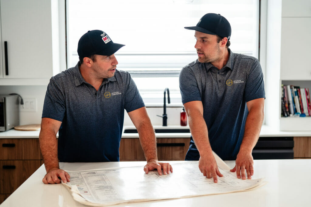 Deux hommes regardent les plans d'un immeuble à logement